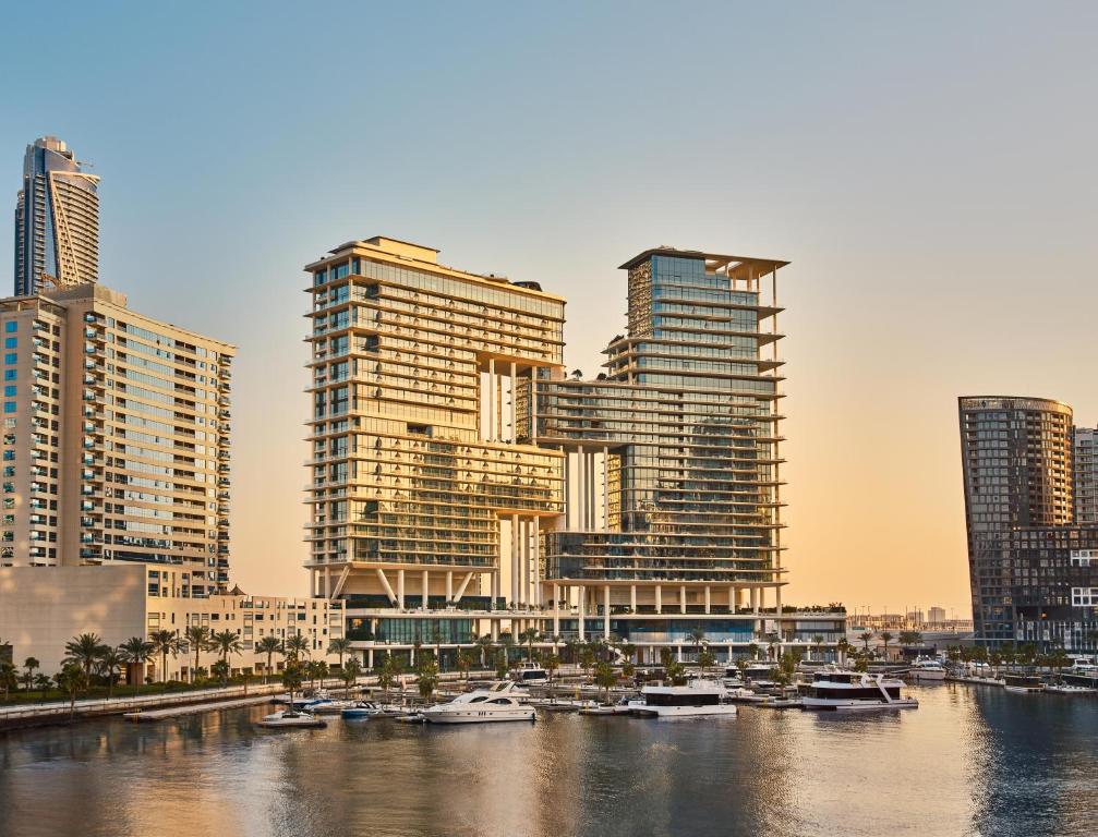 a group of tall buildings next to a river with boats at The Lana - Dorchester Collection in Dubai