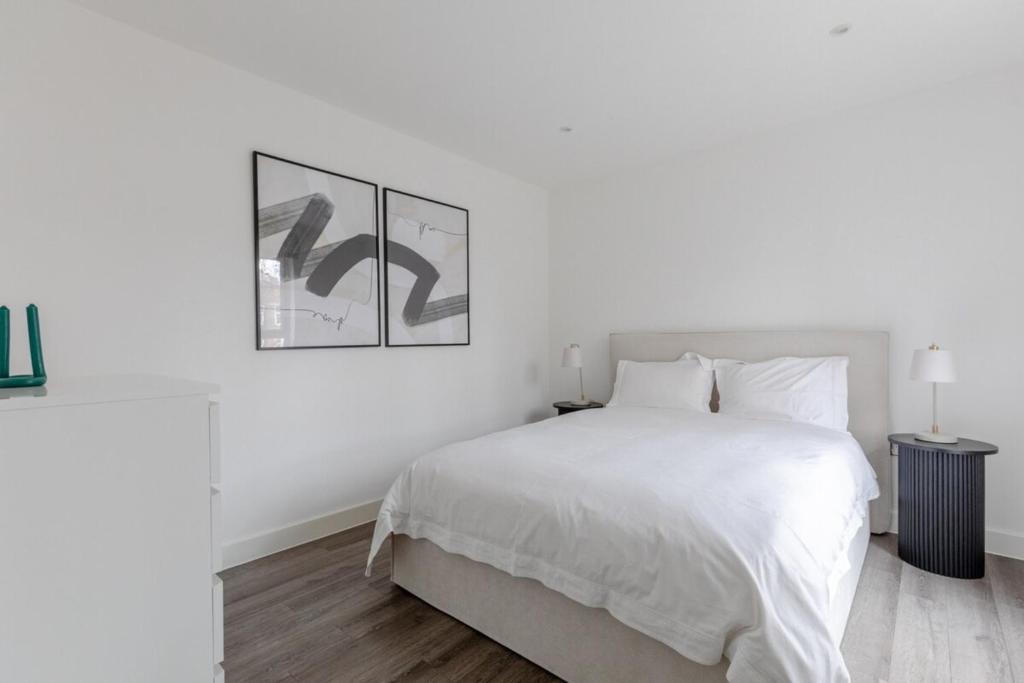 biała sypialnia z łóżkiem i 2 zdjęciami na ścianie w obiekcie Elegant & Serene 2BD Flat wRoof Terrace Hoxton! w Londynie