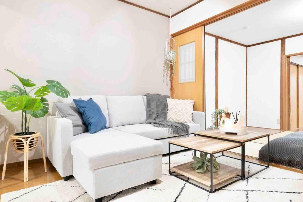 uma sala de estar com um sofá branco e uma mesa em Takii Motomachi Irodori House em Osaka