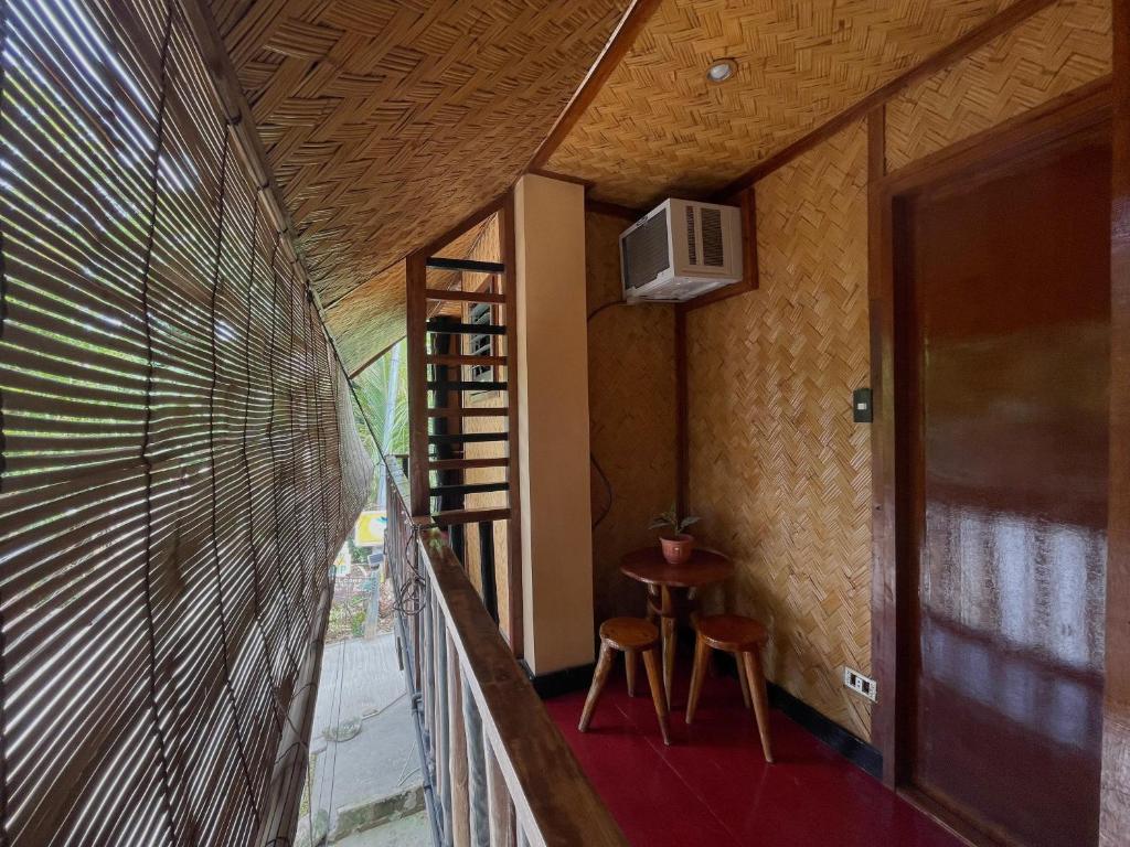 a room with a balcony with a table and stool at Hidden of Cailan Extension Transient House in El Nido