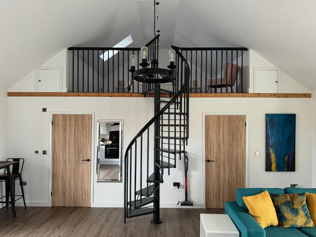 a living room with a spiral staircase and a blue couch at Brooke View Barns No 1 in Norwich