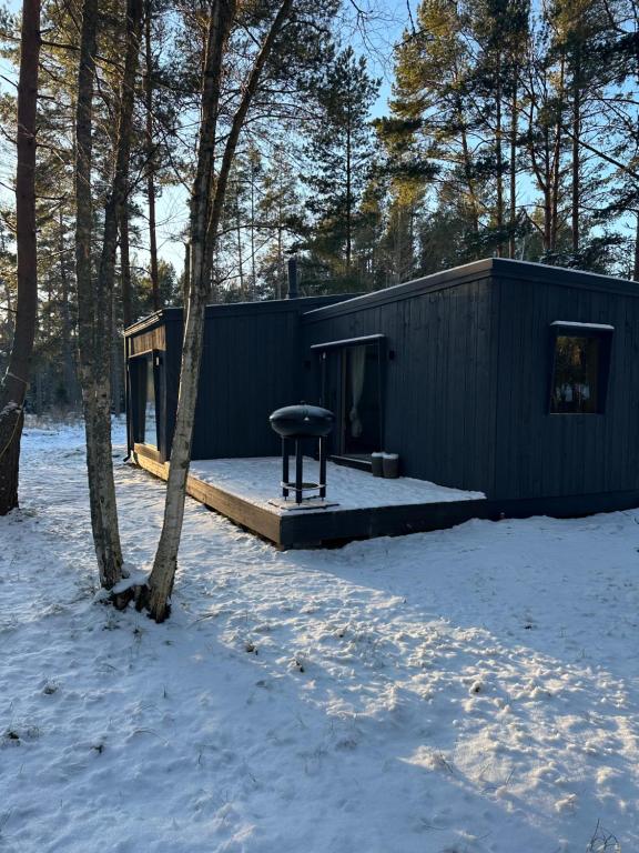 a black building with a picnic table in the snow at The Lighthouse in Pāvilosta