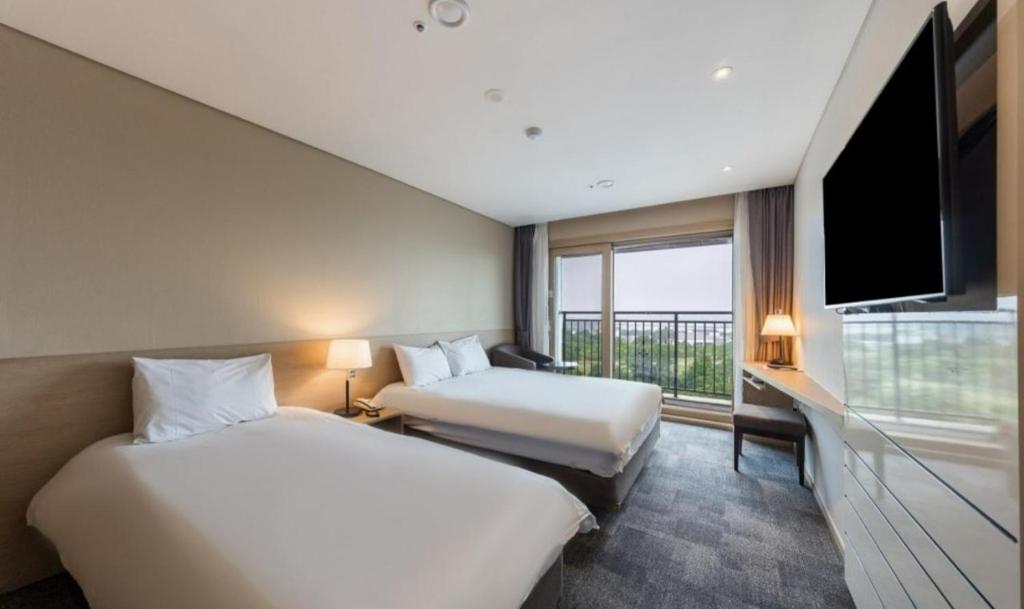 Habitación de hotel con 2 camas y TV de pantalla plana. en The Best Jeju Seongsan en Seogwipo