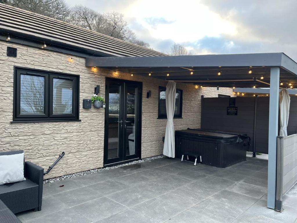 a patio with a grill and a tub under a pergola at Terfyn Hall holiday Apartment 2 in Prestatyn