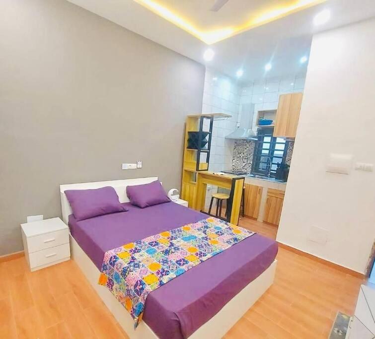 a bedroom with a purple bed and a kitchen at Les 9 Plurielles - Studio 2 KPALIME KOUMA KONDA in Palimé