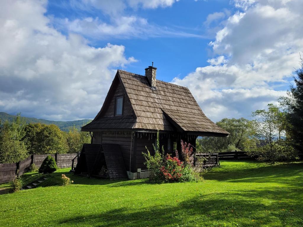 ein altes Haus auf einem Feld mit grünem Rasen in der Unterkunft Chatka Kudłatka in Wetlina