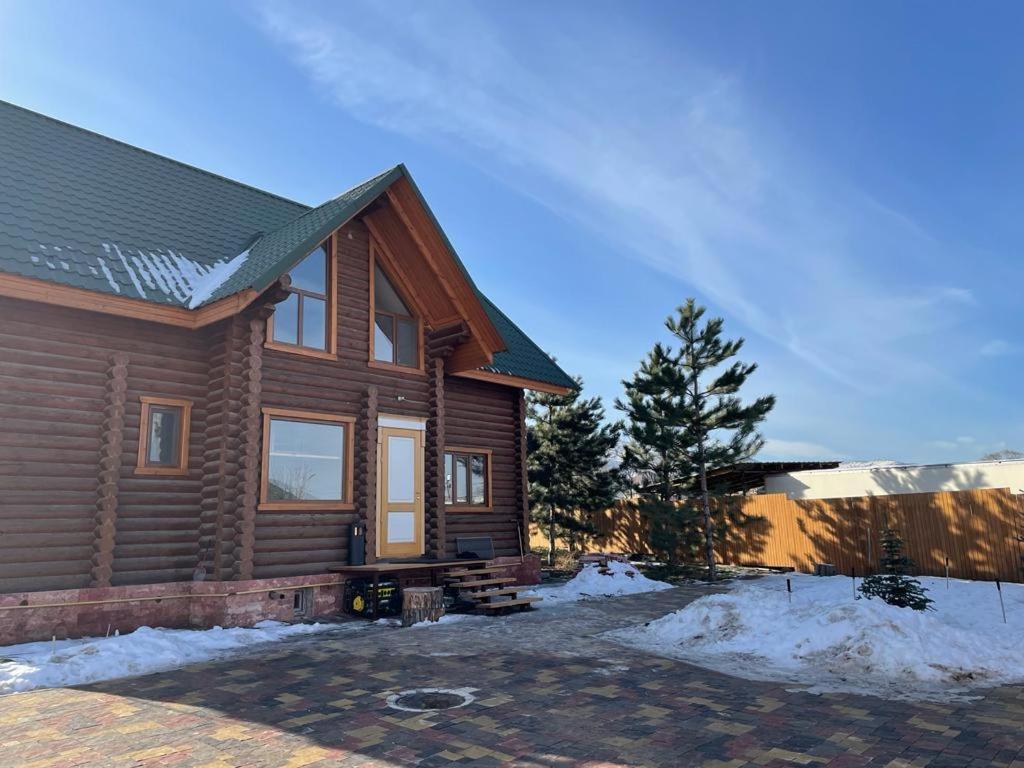 een houten huis met sneeuw ervoor bij eco-house Talhiz in Talghar