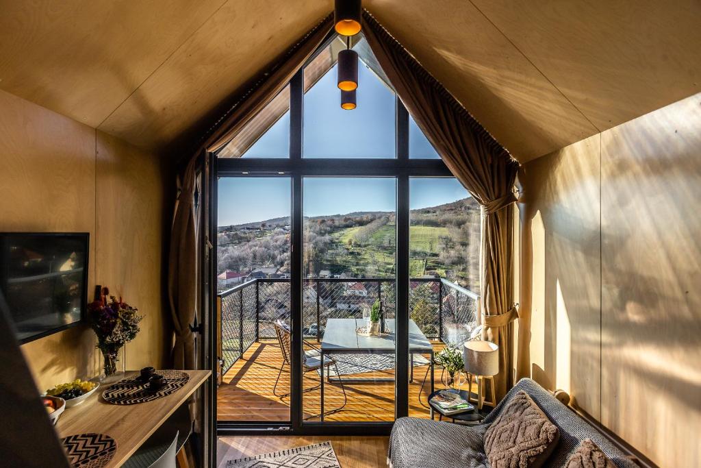 een kamer met een groot raam met een tafel en een balkon bij Moose & Reindeer Cabin Chalets With A Panoramic View - Happy Rentals in Hosszúhétény-Szőlőhegy