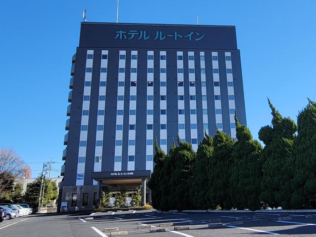 un bâtiment avec un panneau sur son côté dans l'établissement HOTEL ROUTE-INN Ota Minami -Route 407-, à Ota