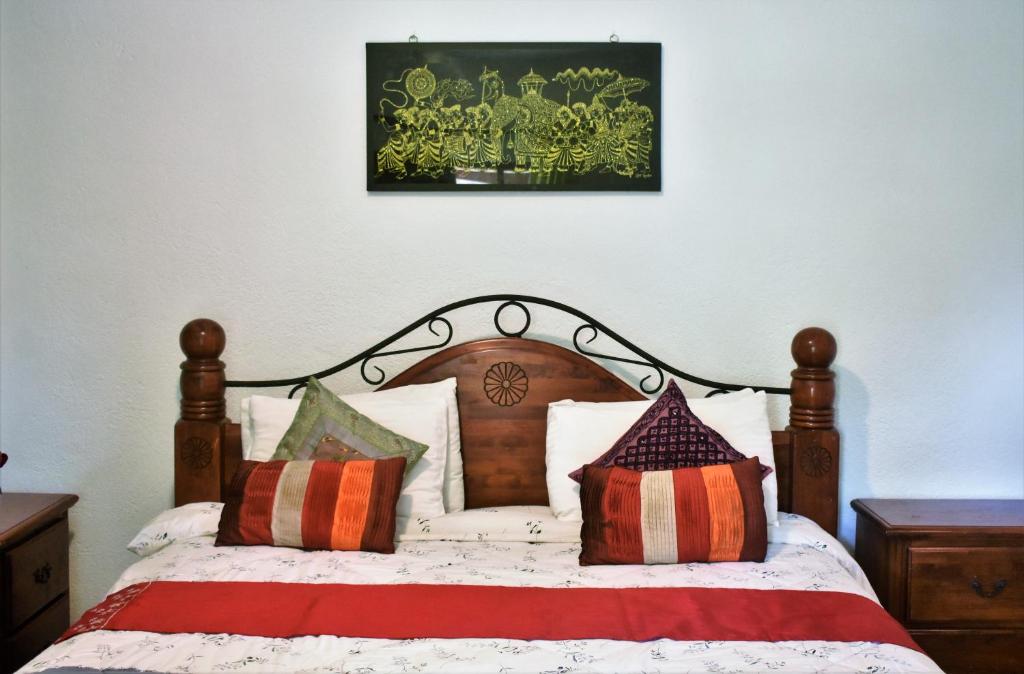 een slaapkamer met een houten bed met kussens erop bij Deer Point Hotel Kandy in Kandy