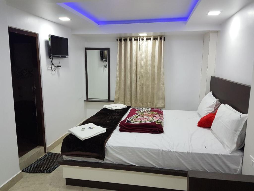 um quarto com uma grande cama branca com almofadas vermelhas em Prakash home stay em Ooty