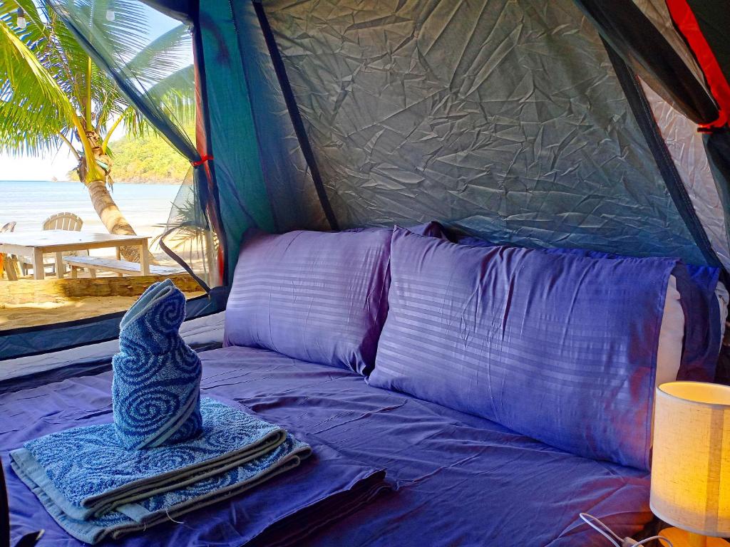 Una cama en una tienda con una toalla. en BH Beachfront Mini Glamping Tent, en El Nido