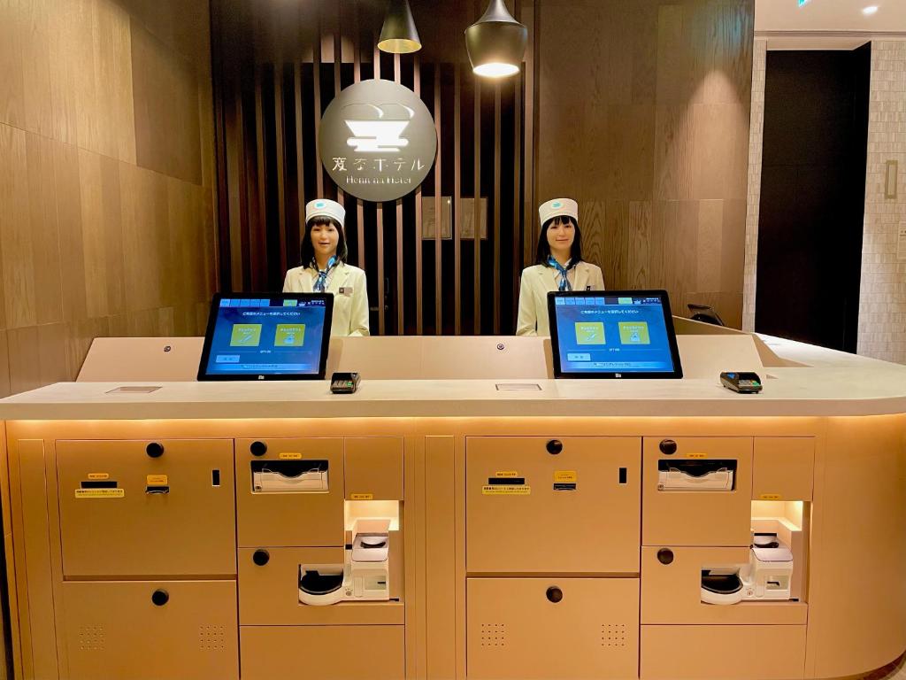 東京にある変なホテル東京 銀座の二人のシェフがラップトップを持ってカウンターの後ろに立っている