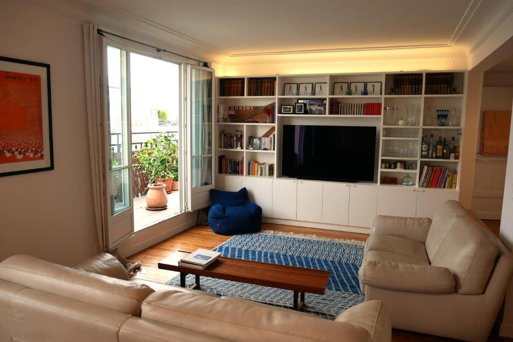 een woonkamer met een bank en een tv bij Champerret in Parijs