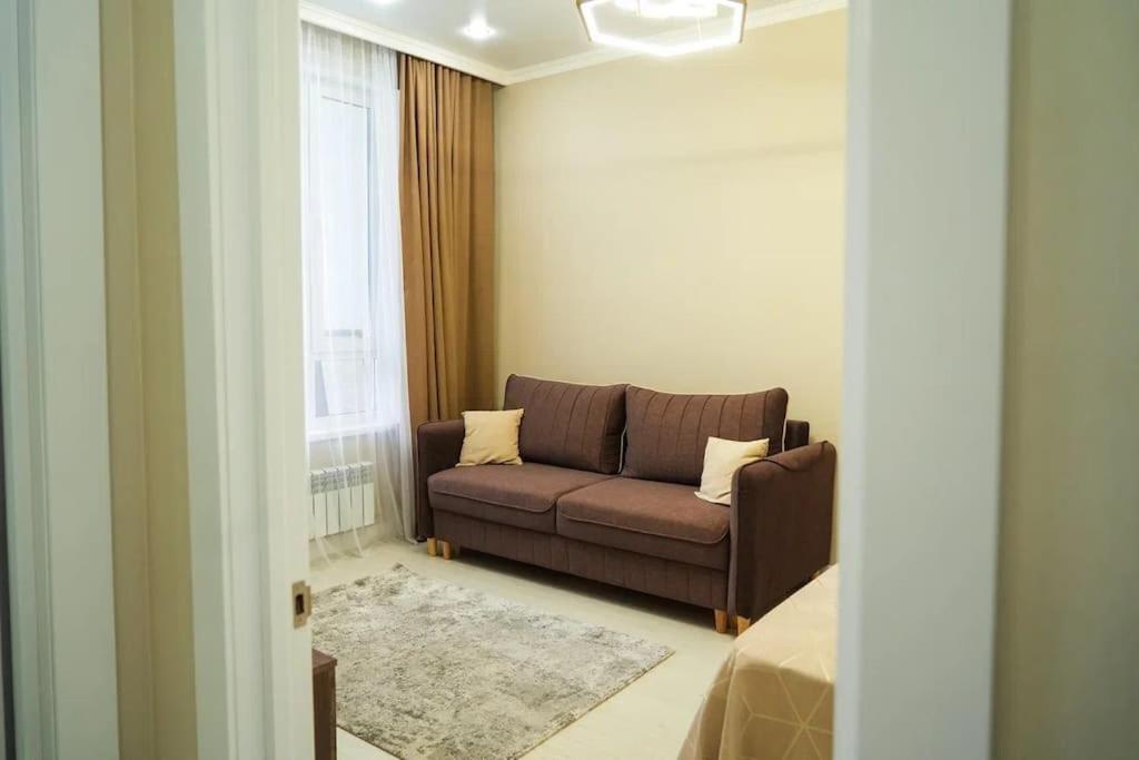a living room with a couch and a window at apartment Tandau Astana in Taldykolʼ