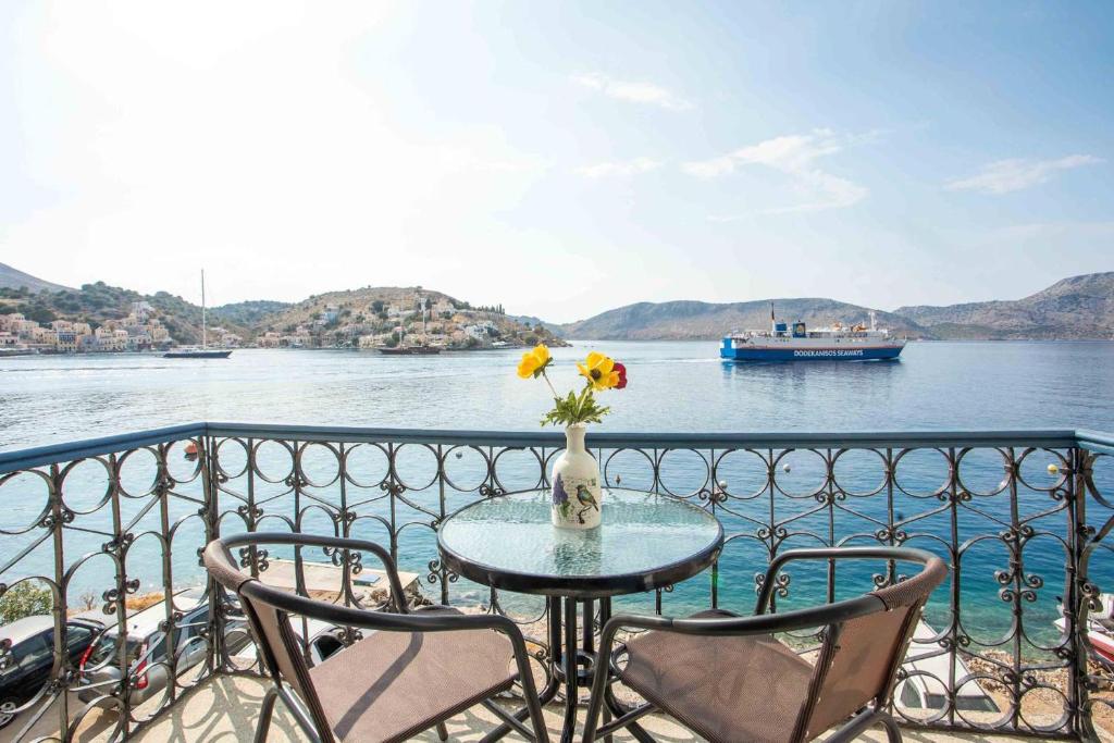 a table with chairs and a vase of flowers on a balcony at Myrsini's House in Symi