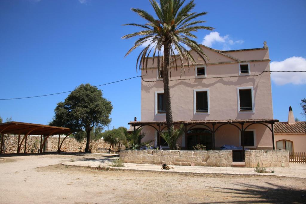 una casa con una palmera delante de ella en Finca Santa Maria Magdalena, en Ciutadella