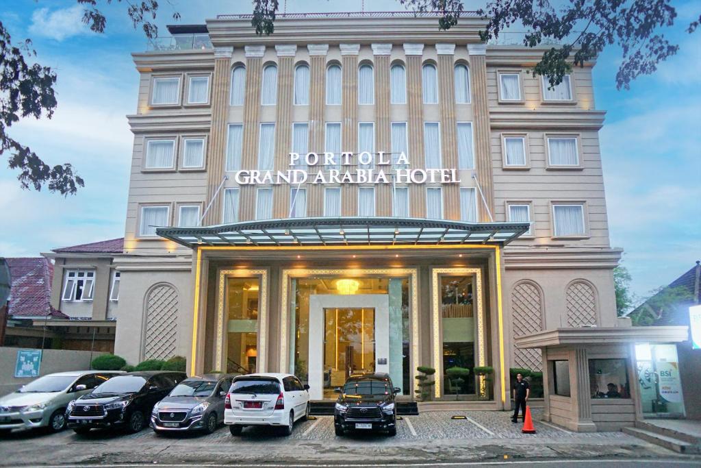 Portola Grand Arabia Hotel في باندا أسيه: فندق فيه سيارات تقف امامه