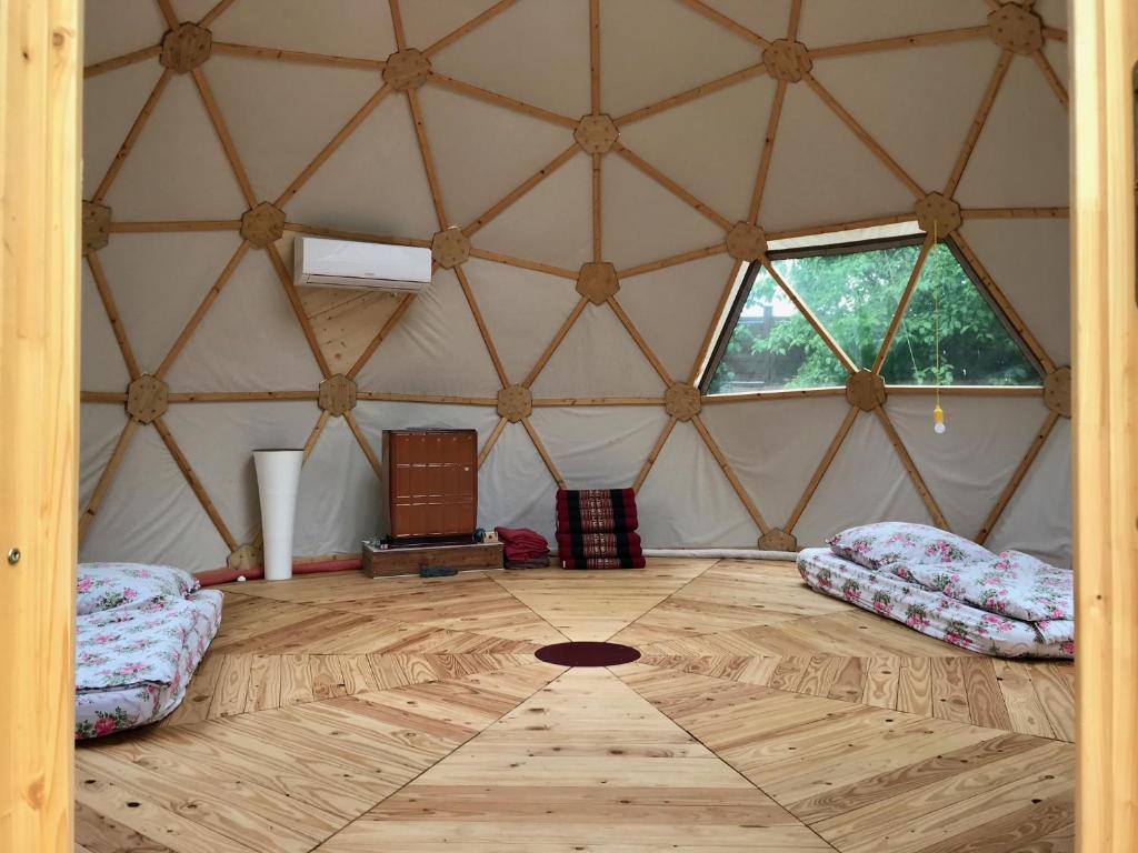 a room with two beds and a wooden floor in a yurt at Geo Dome 