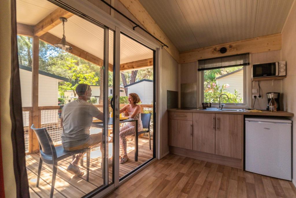 a man and woman sitting at a table in a tiny house at Domaine La Pinède Enchantée in Argelès-sur-Mer