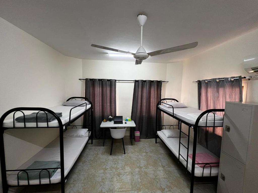 a room with three bunk beds and a sink at Viva Hostel Group Muscat in Muscat