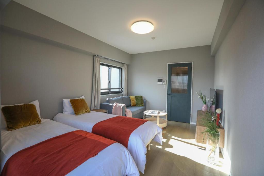 een kamer met 2 bedden en een woonkamer bij One-asakusa in Tokyo