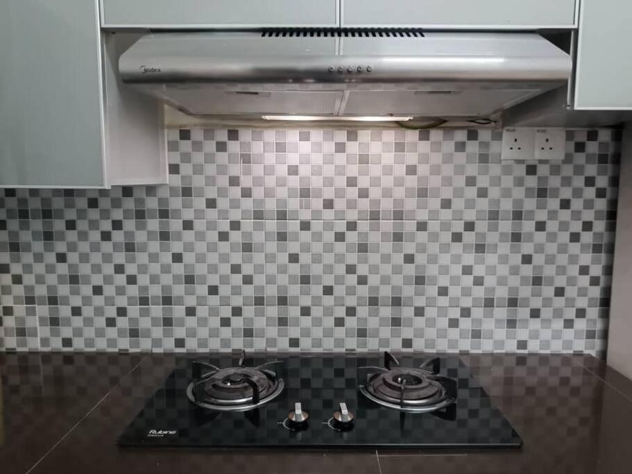 a stove top in a kitchen with a tiled wall at Homestay HNH Melaka (Corner Lot) in Melaka