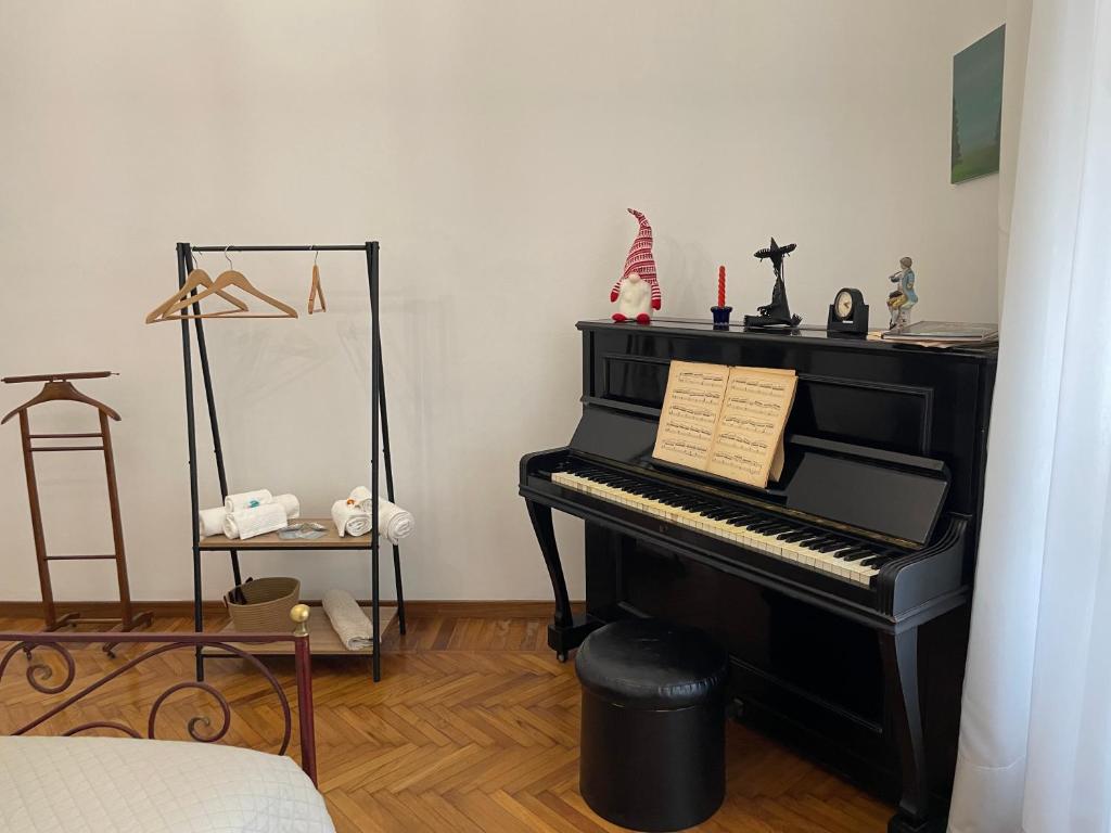 un pianoforte nero in una stanza con un cartello sopra di Coli's House a Torino