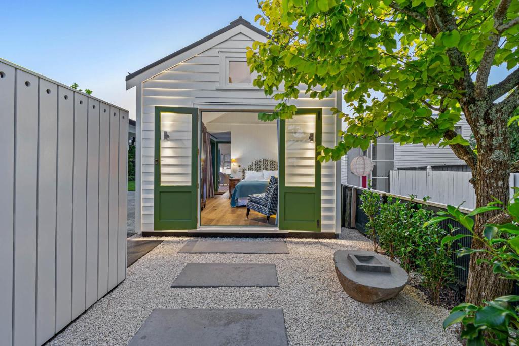 uma pequena casa com portas verdes e uma cerca em Augusta Hut em Auckland