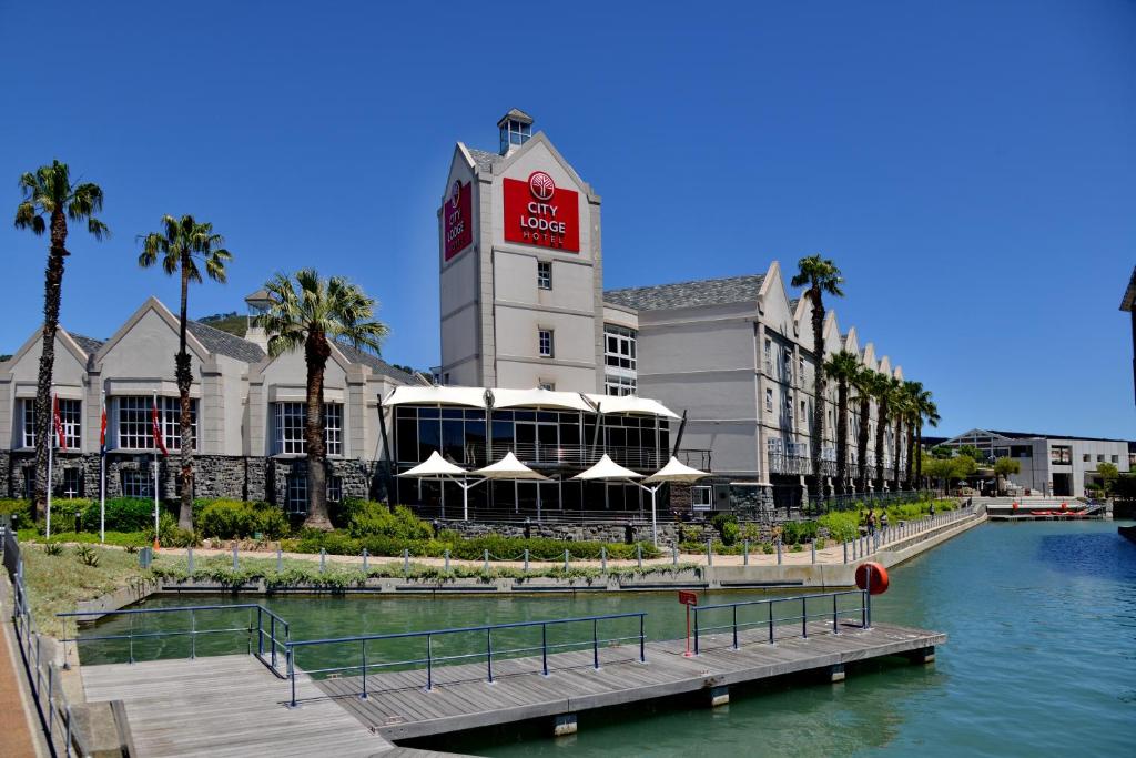 un edificio con una torre de reloj junto a un cuerpo de agua en City Lodge Hotel V&A Waterfront, en Ciudad del Cabo