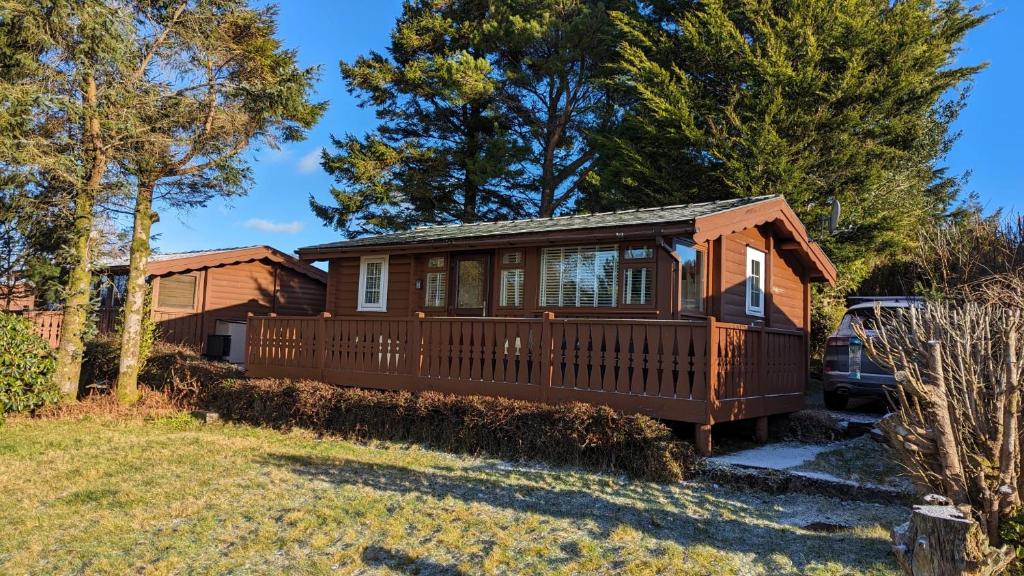 a home with a deck and a house at Snowdonia Log cabin in Trawsfynydd