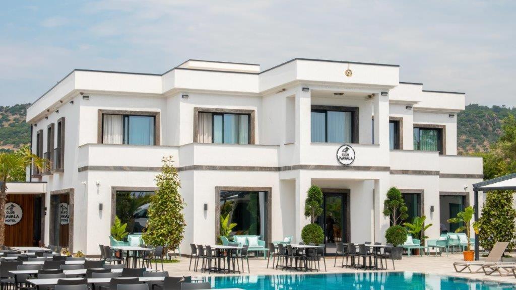 un edificio blanco con una piscina frente a él en Club Kavala Beach Hotel Assos en Behramkale