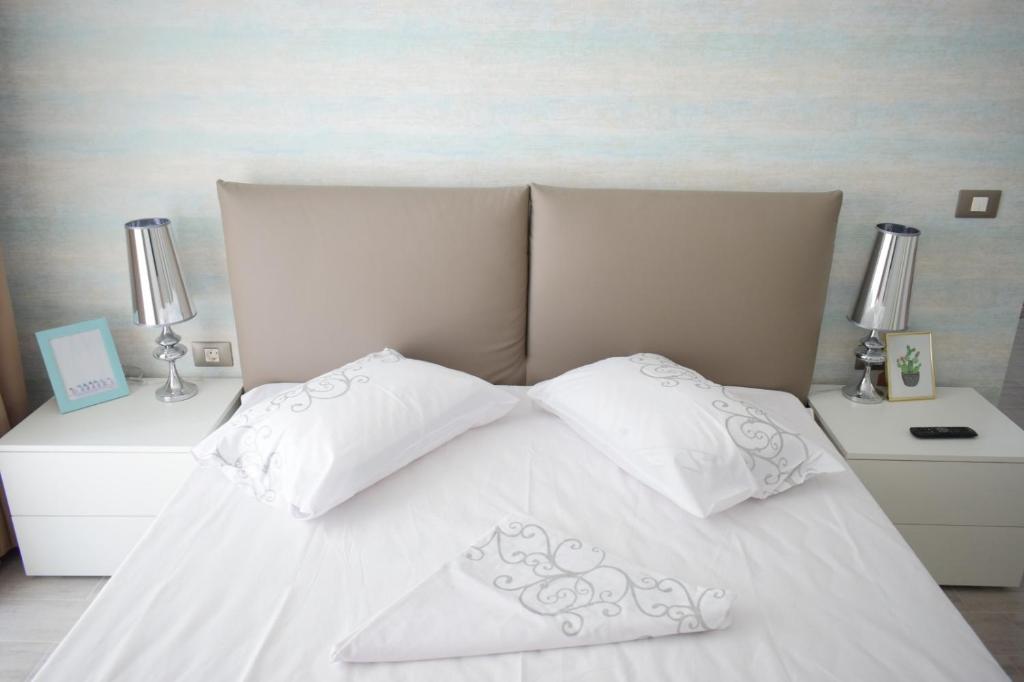 1 cama blanca con 2 almohadas y 2 mesitas de noche en ALZ Beach Apartments in Alezzi Beach Resort, en Mamaia Nord – Năvodari