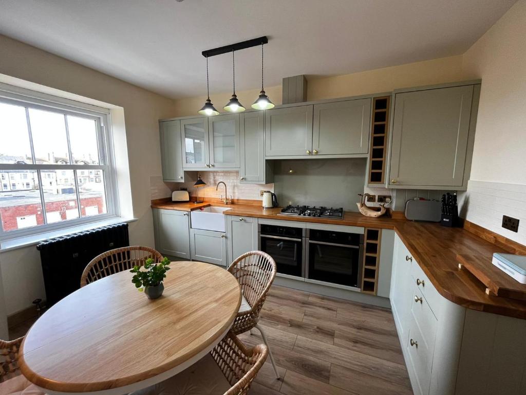 uma cozinha com uma mesa de madeira, uma mesa e cadeiras em Luxury Penthouse Apartment em Lowestoft