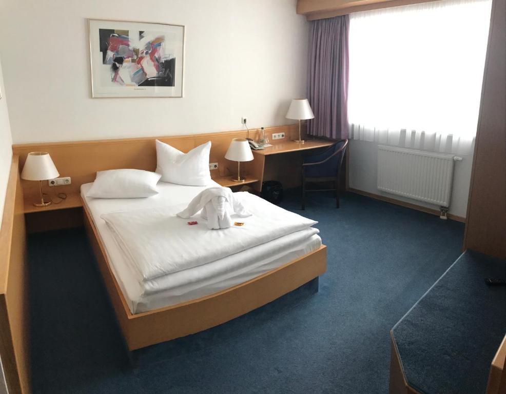 a hotel room with a bed with a towel on it at Hotel Bavaria Brehna in Brehna