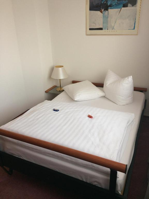 a bed in a room with white sheets and pillows at Hotel Bavaria Brehna in Brehna