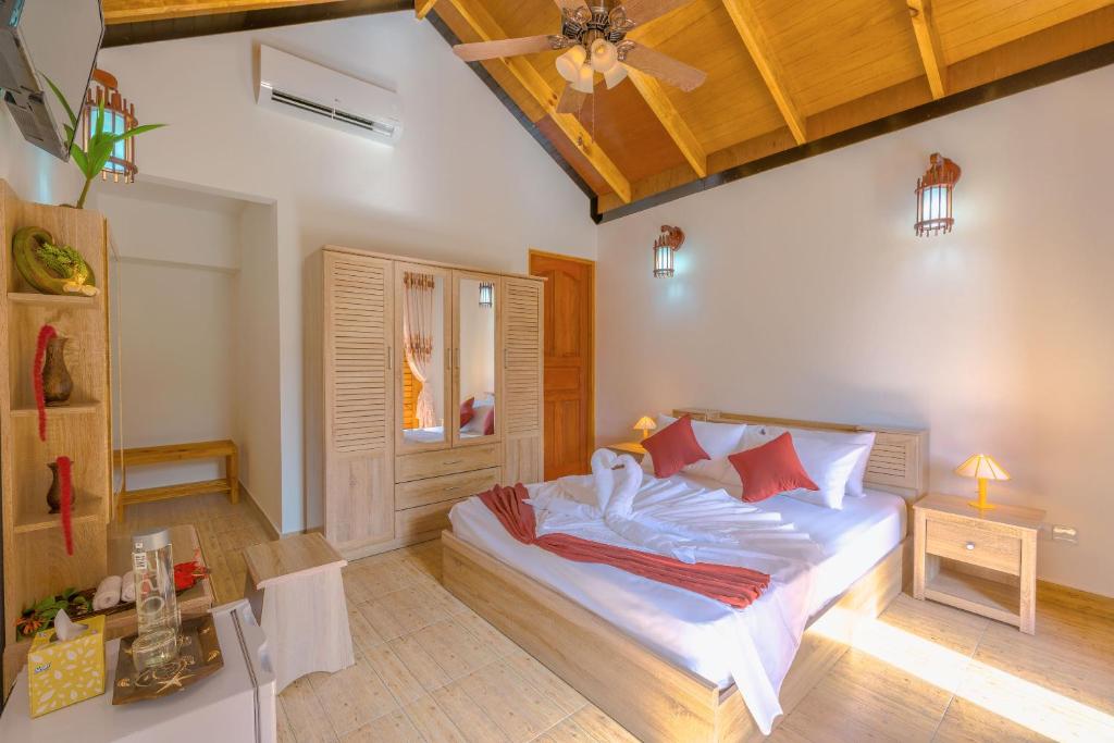 Schlafzimmer mit einem Bett mit weißer Bettwäsche und roten Kissen in der Unterkunft Sabba Summer Suite , Fodhdhoo in Fodhdhoo