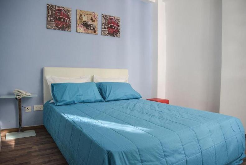 a bed with a blue comforter in a bedroom at The Tony in Nicosia