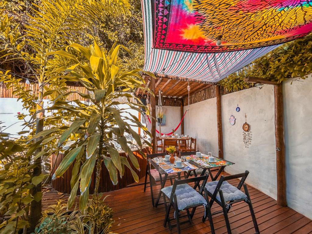 un patio con mesa y sillas y un techo colorido. en Maruê Guesthouse Porto de Pedras, en Porto de Pedras