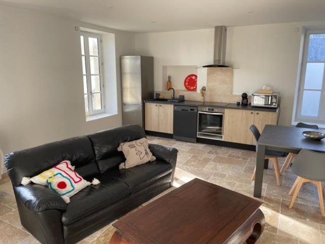 uma sala de estar com um sofá preto e uma cozinha em Gîte de Fontiville em Veigné