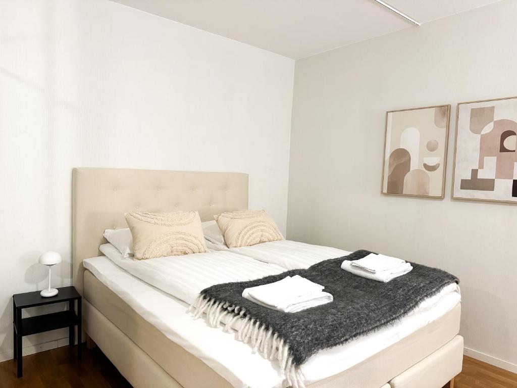 Aurora City Studio في روفانييمي: غرفة نوم بيضاء مع سرير وبطانية سوداء