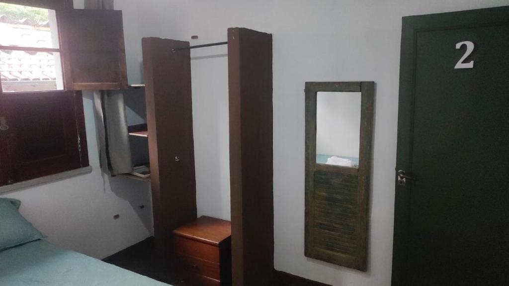 a bedroom with a mirror next to a bed at Sôsouza in Belo Horizonte