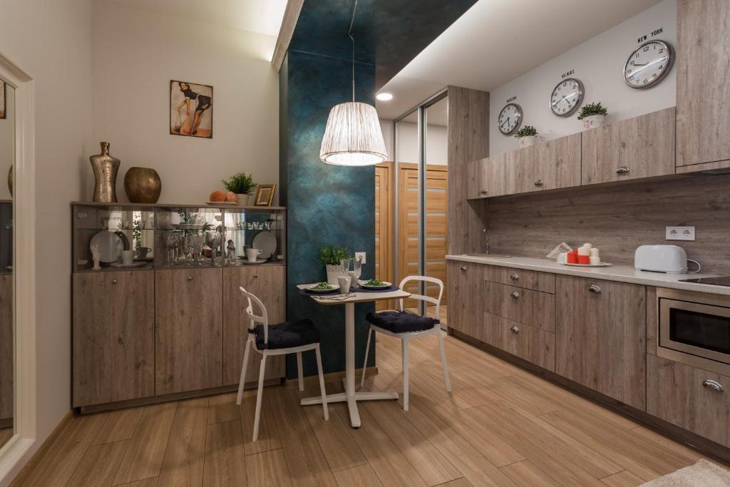 Raugyklos apartamentai في فيلنيوس: مطبخ بدولاب خشبي وطاولة وكراسي