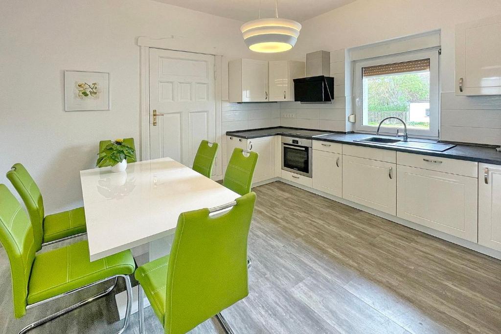 uma cozinha com uma mesa branca e cadeiras verdes em Ferienwohnung Malve em Lübbenau