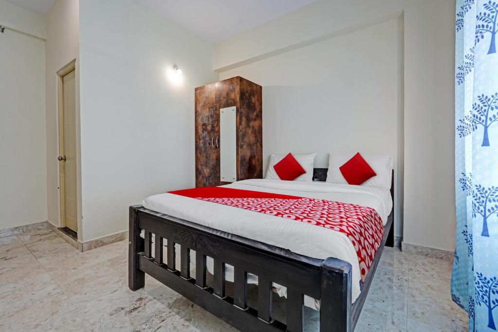 1 dormitorio con 1 cama grande con almohadas rojas en Oyo Flagship Sri Chowdeshwari Boarding And Lodging, en Bangalore