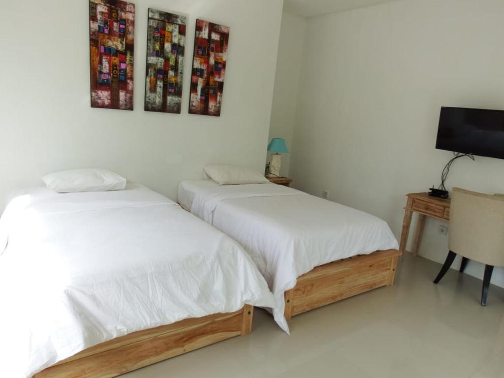 two beds in a white room with a tv at Deepblue vila in Pulukan