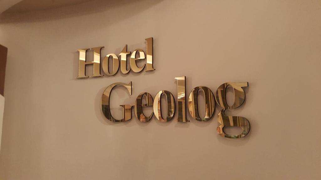 un cartel de hotel colgado en una pared en Hotel Geolog, en Surgut