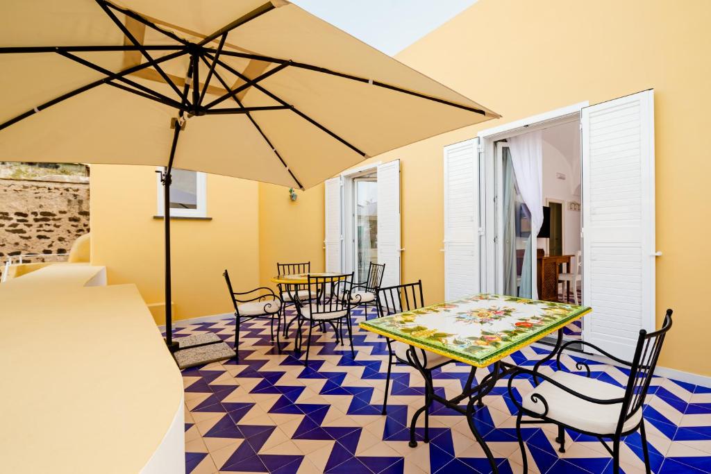 um pátio com uma mesa, cadeiras e um guarda-sol em Hotel Da Raffaele em Ischia