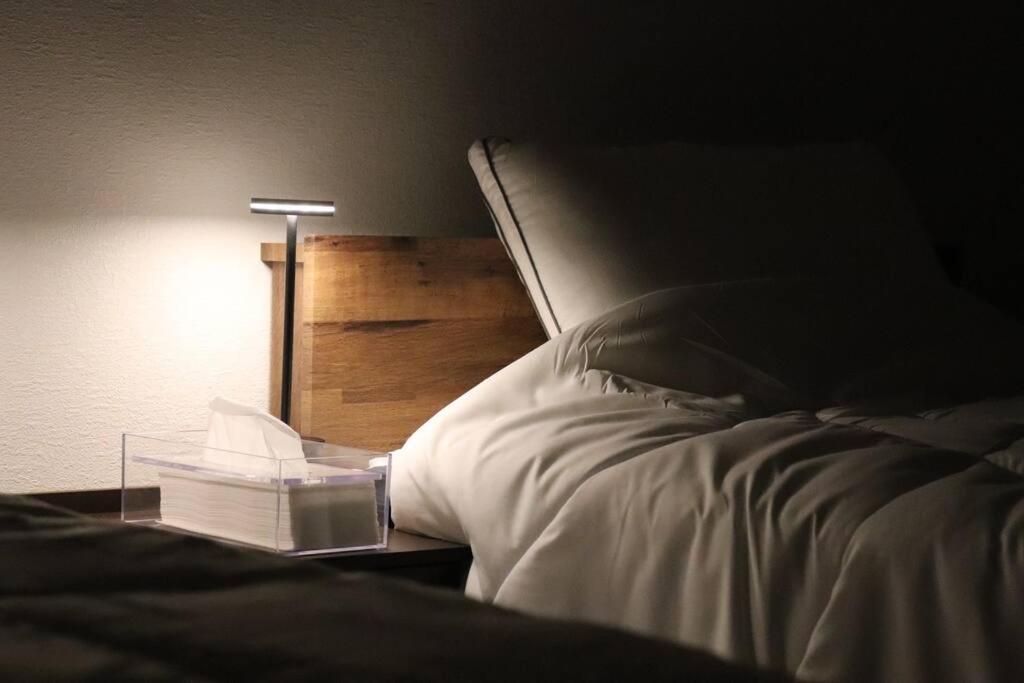 a bed with a lamp and a book on it at シアタールーム付き！駅徒歩7分の好立地！【藍Restvillage松本】 in Matsumoto
