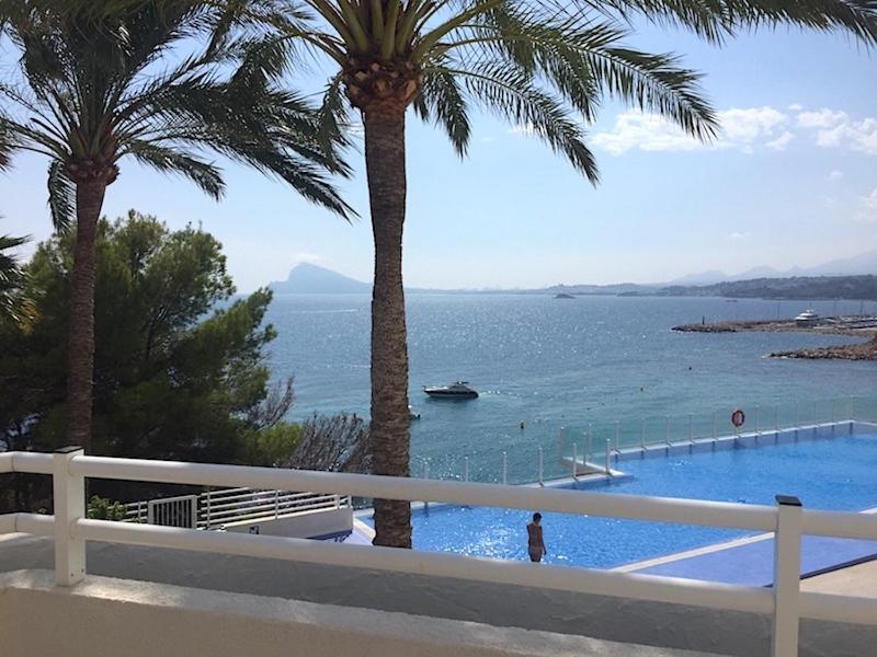 uma vista para uma piscina com palmeiras e para o oceano em Apartment Panorama 2 em Altea